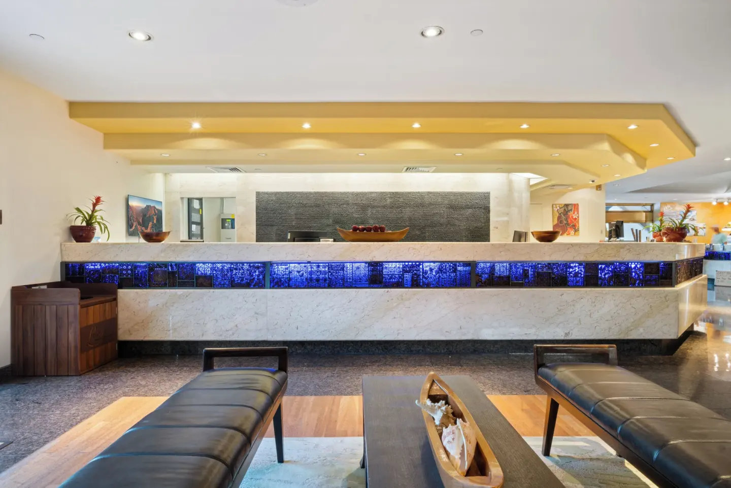 Lobby seating faces the illuminated front desk at Luana Waikiki Hotel & Suites.