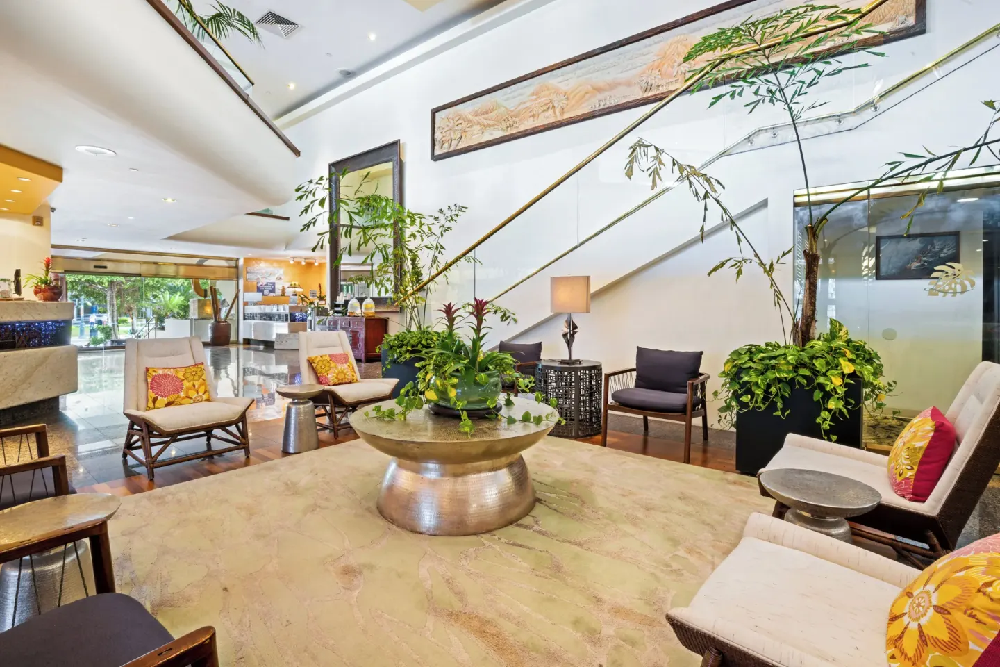 Lobby seating at Luana Waikiki Hotel & Suites with staircase, plants, and reception area in view.