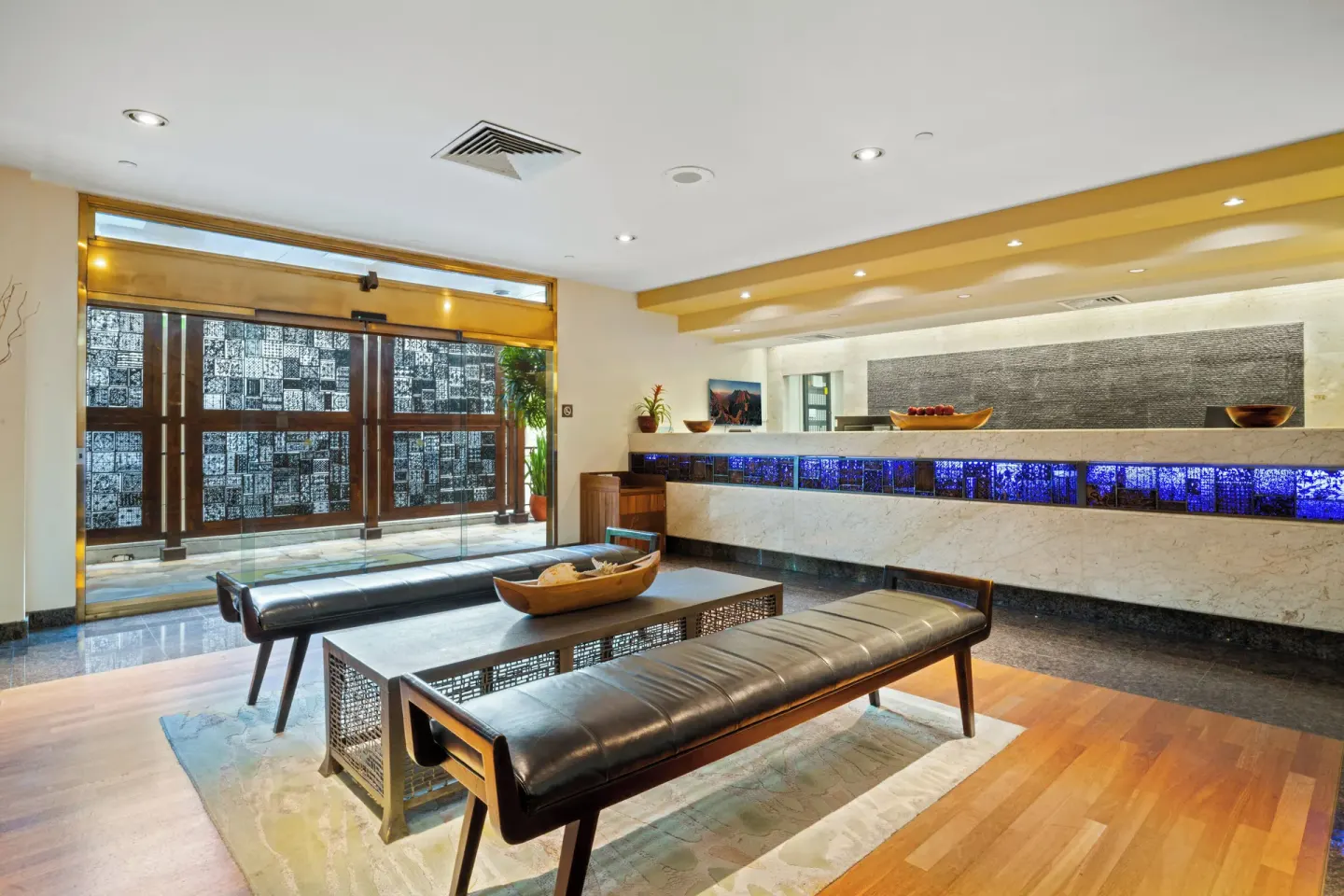 Reception area at Luana Waikiki Hotel & Suites with front desk, benches, and glass entry doors.