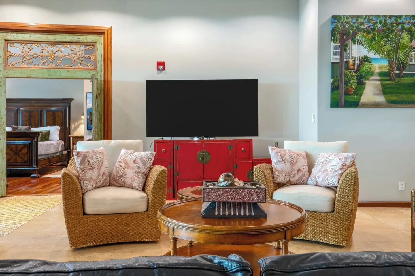 Resort lounge with wicker chairs, a TV, and tropical artwork at Luana Waikiki Hotel & Suites.
