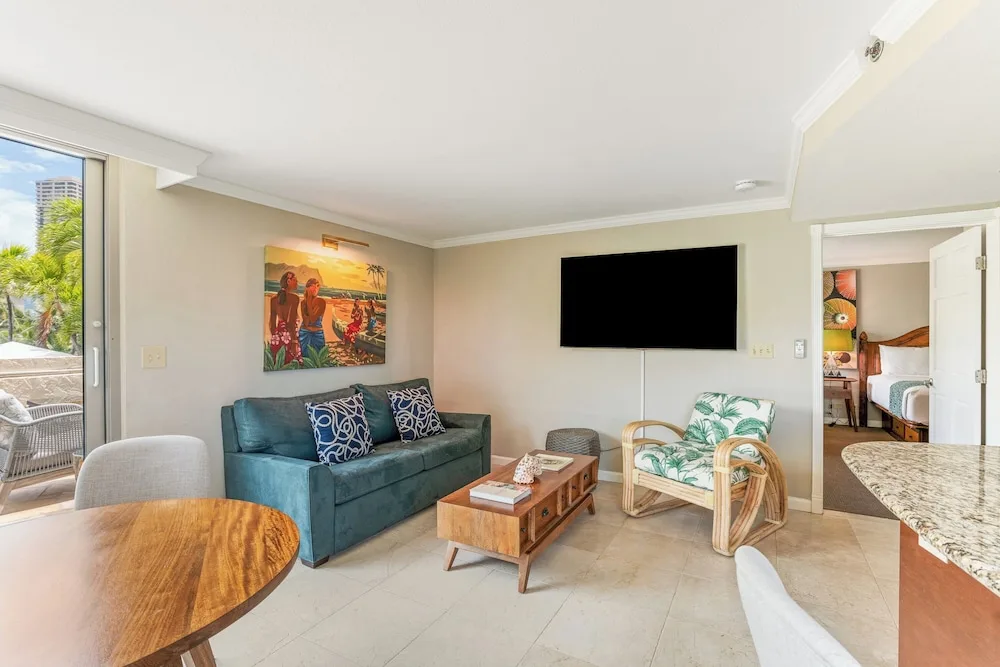 Suite living area with sofa, wall TV, and kitchenette counter at Luana Waikiki Hotel & Suites.