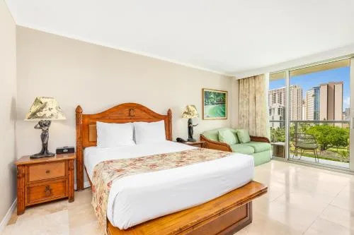 City View Bed with Sofa Bed guest room at Luana Waikiki Hotel & Suites with sofa beside large windows.