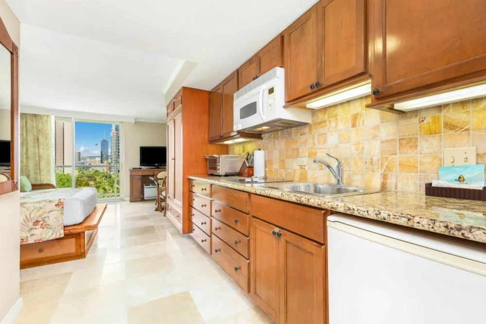 City View Bed with Sofa Bed room at Luana Waikiki Hotel & Suites with kitchenette and bed by windows.