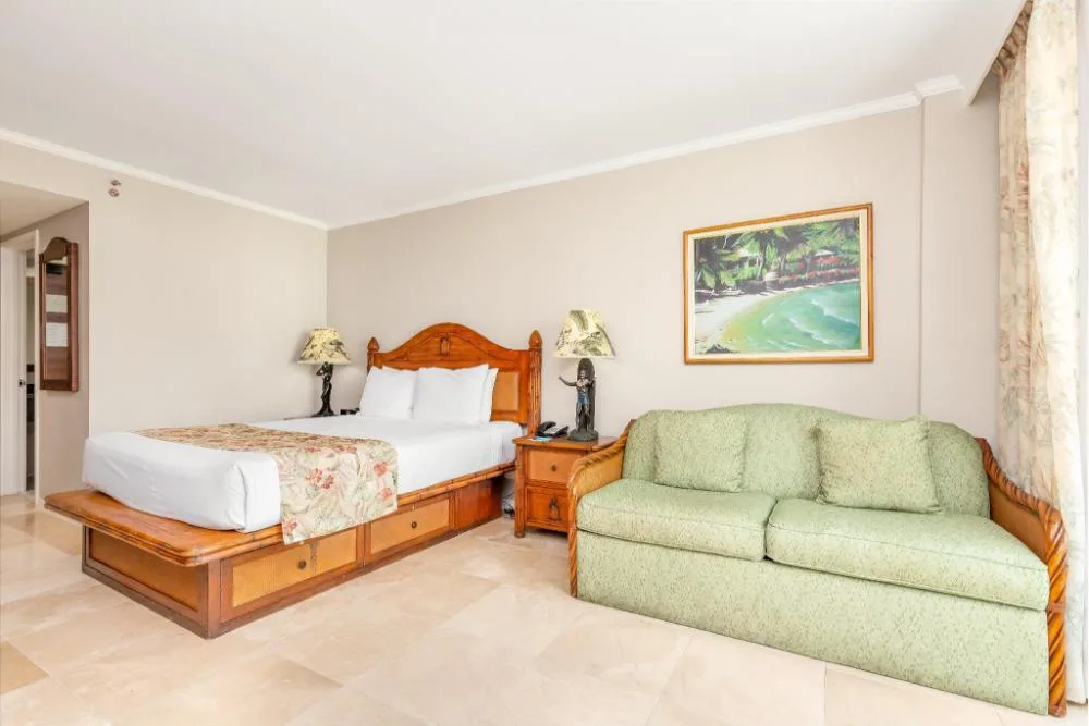City View Studio Suite with king bed and green sofa at Luana Waikiki Hotel & Suites.
