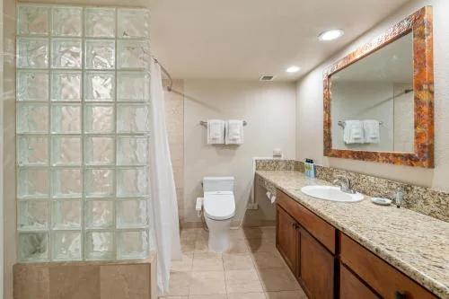 Family One Bedroom Suite bathroom with vanity and glass-block shower at Luana Waikiki Hotel & Suites.