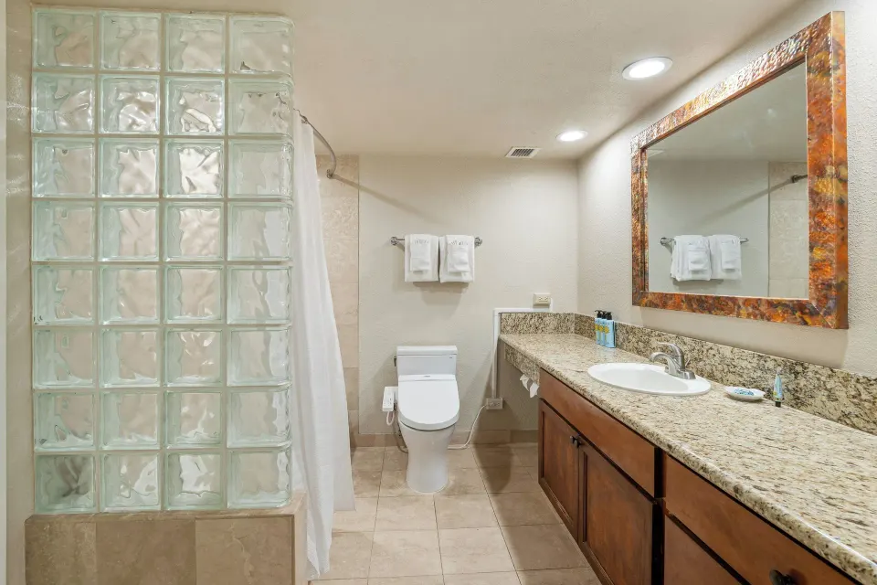 Family Suite bathroom with granite vanity and glass-block shower at Luana Waikiki Hotel & Suites.
