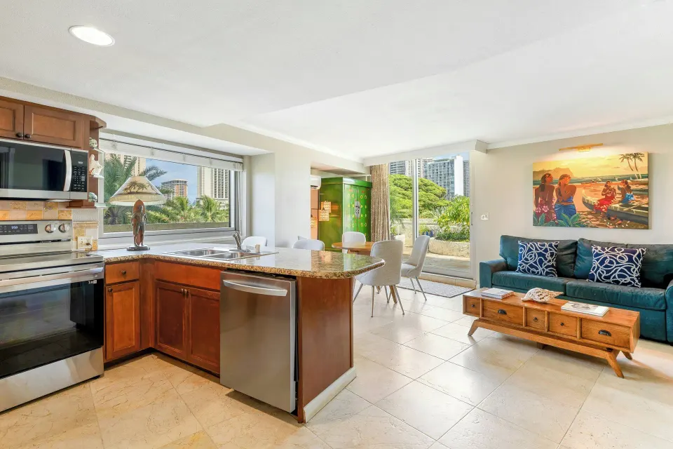 Family suite kitchen and living area at Luana Waikiki Hotel & Suites with appliances and sofa.