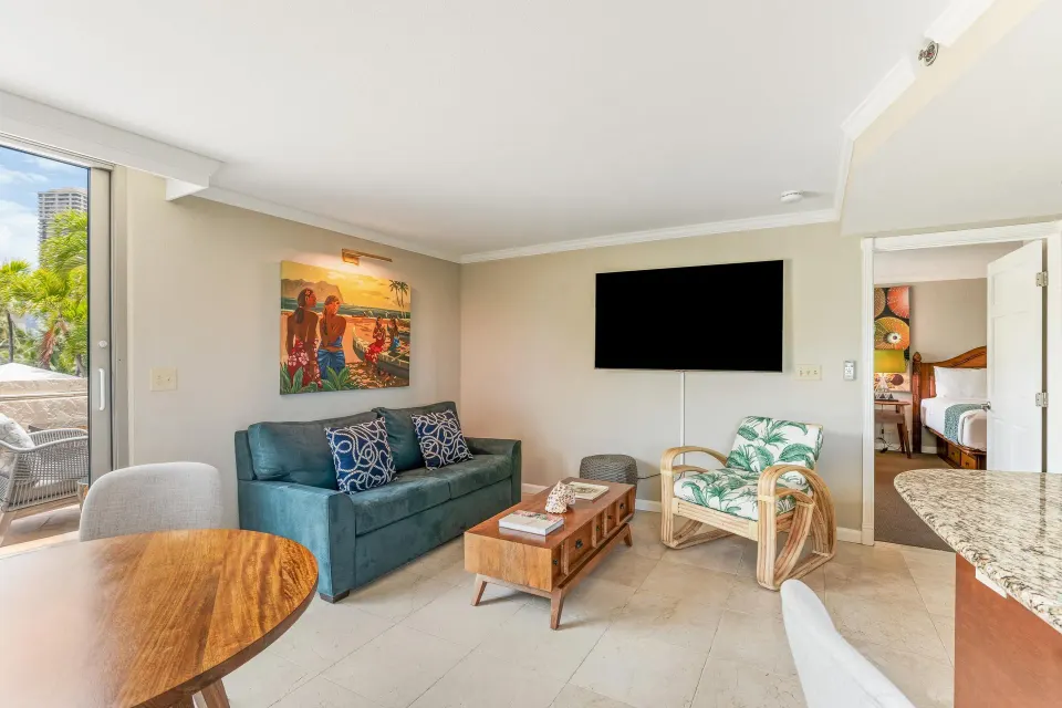 Family Suite living room with sofa, TV, terrace, and bedroom doorway at Luana Waikiki Hotel & Suites.