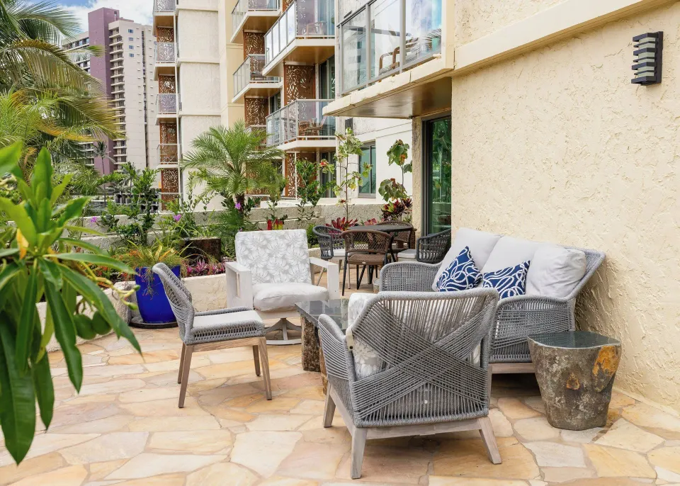 Furnished patio outside a family suite at Luana Waikiki Hotel & Suites with palms and balconies nearby.