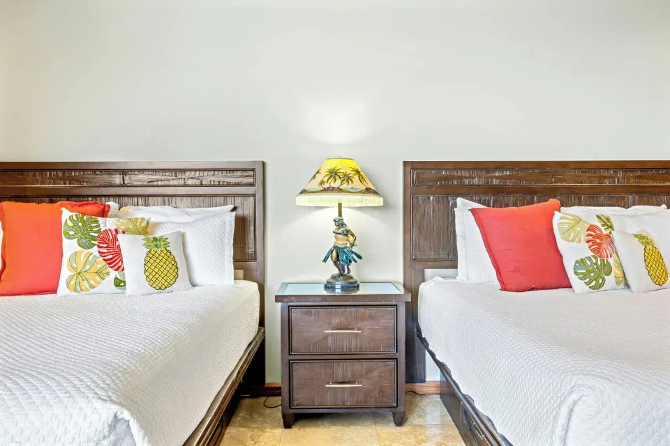 Two beds with tropical pillows in the Mezzanine Level Studio Suite at Luana Waikiki Hotel & Suites.