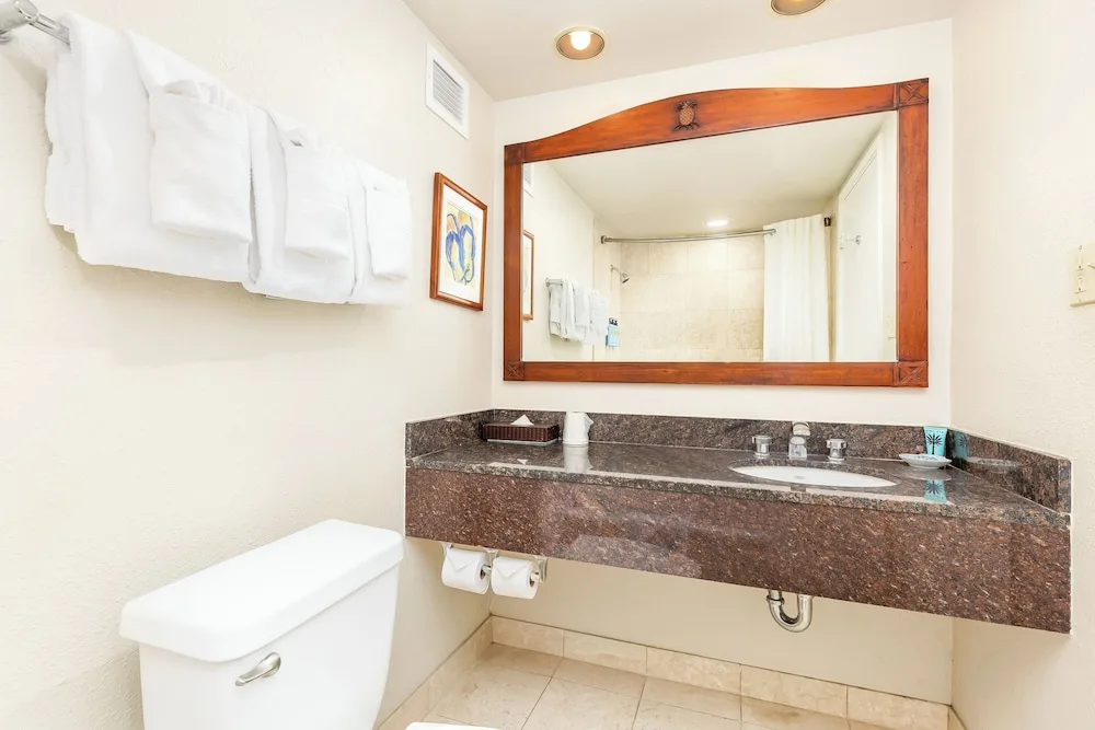 Bathroom vanity with towels and large mirror at Luana Waikiki Hotel & Suites.