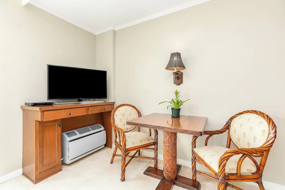 Dining table, wicker chairs, TV cabinet, and wall sconce at Luana Waikiki Hotel & Suites.