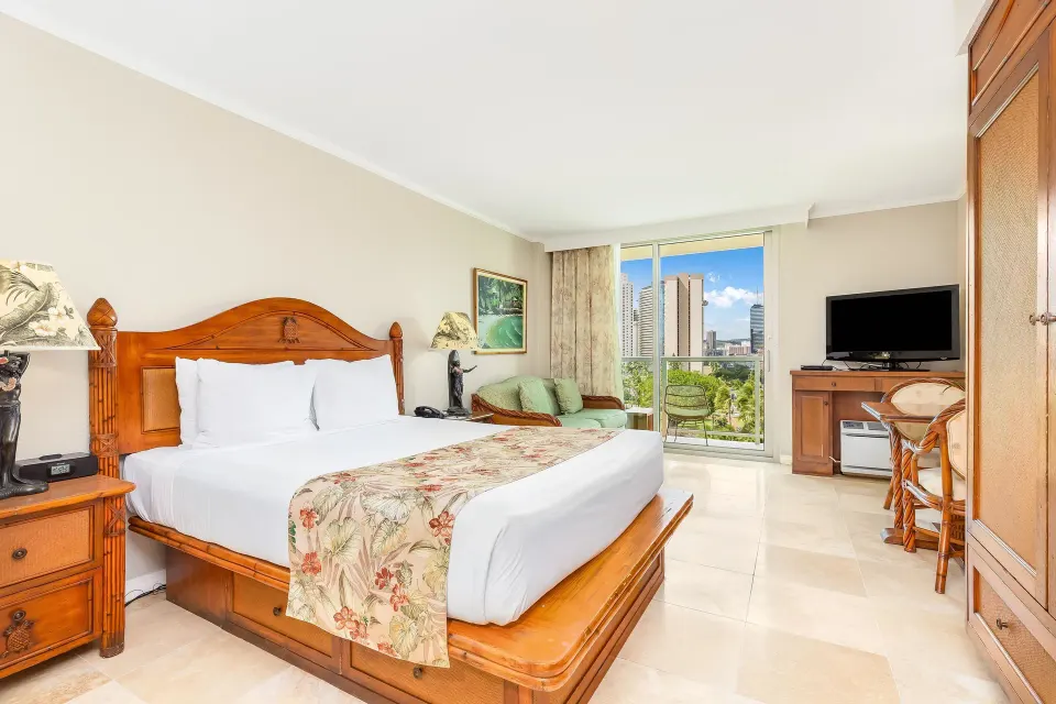 City view room with king bed and balcony seating at Luana Waikiki Hotel & Suites.