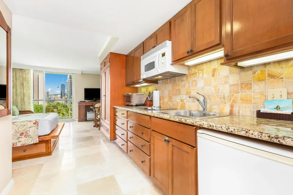 Wood-cabinet kitchenette beside the guest room at Luana Waikiki Hotel & Suites.