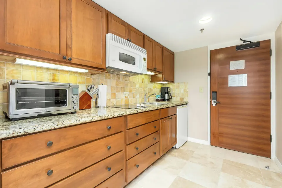 Room kitchenette with wood cabinets and appliances at Luana Waikiki Hotel & Suites.