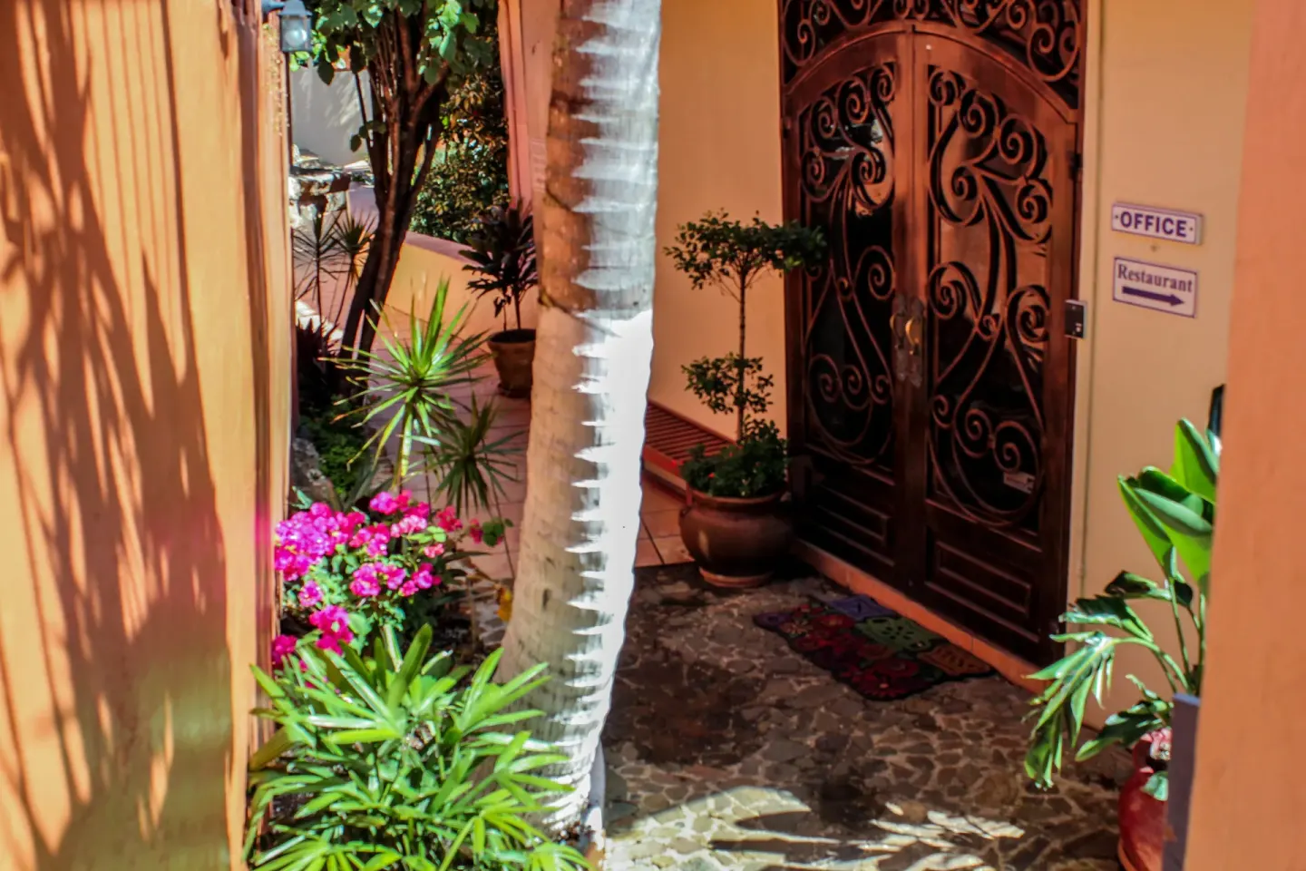 Garden walkway with ornate doors and office and restaurant signs at Mafolie Hotel.