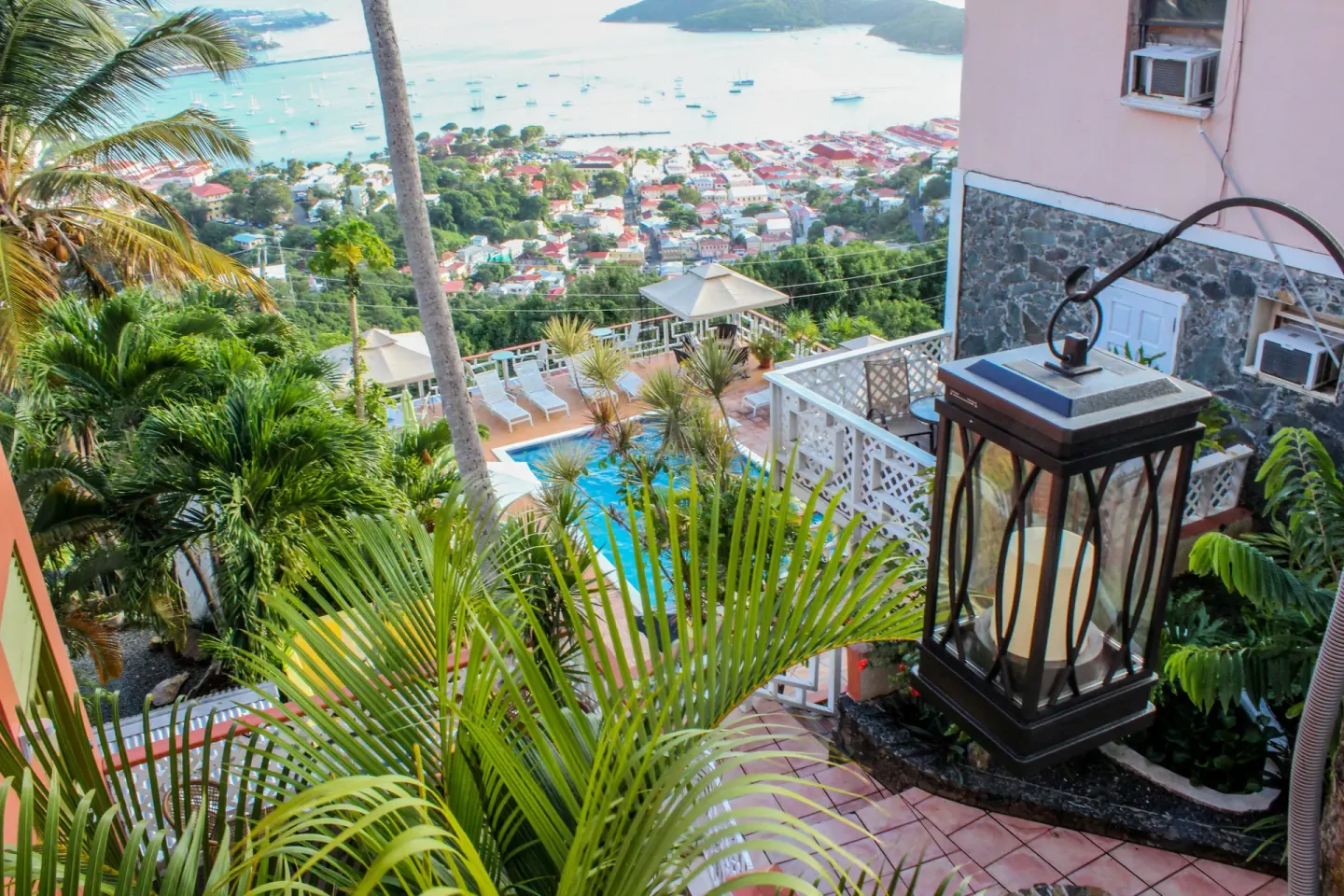 Lantern and palms overlook the pool, hillside town, and harbor at Mafolie Hotel.