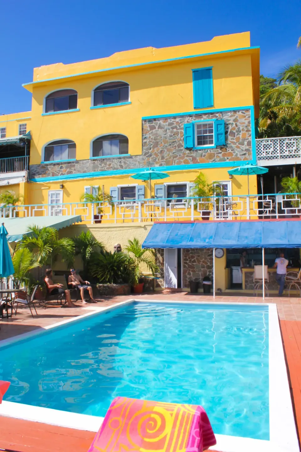 The swimming pool sits below yellow guest buildings at Mafolie Hotel.