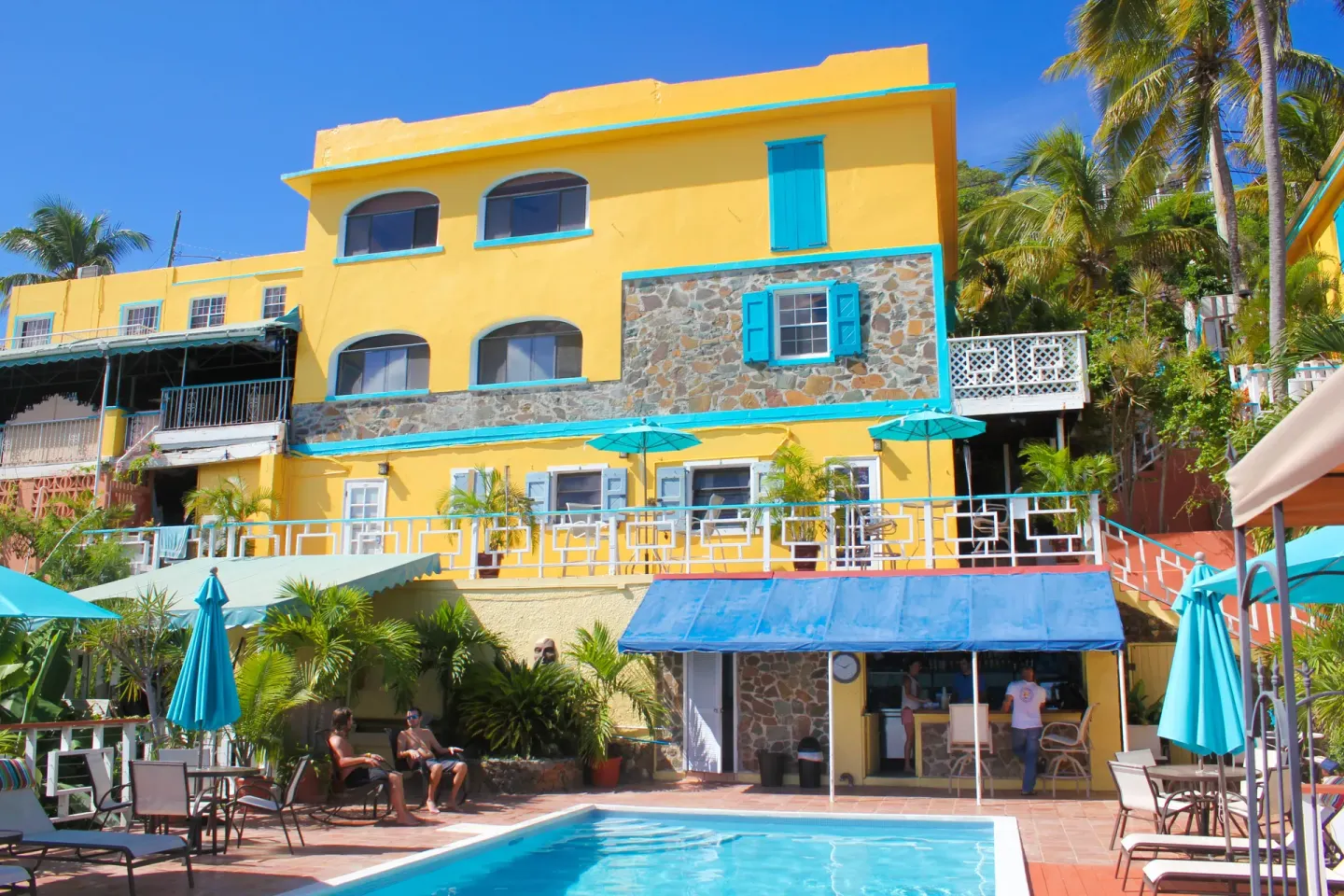 Pool deck, umbrellas, and yellow hillside buildings at Mafolie Hotel.