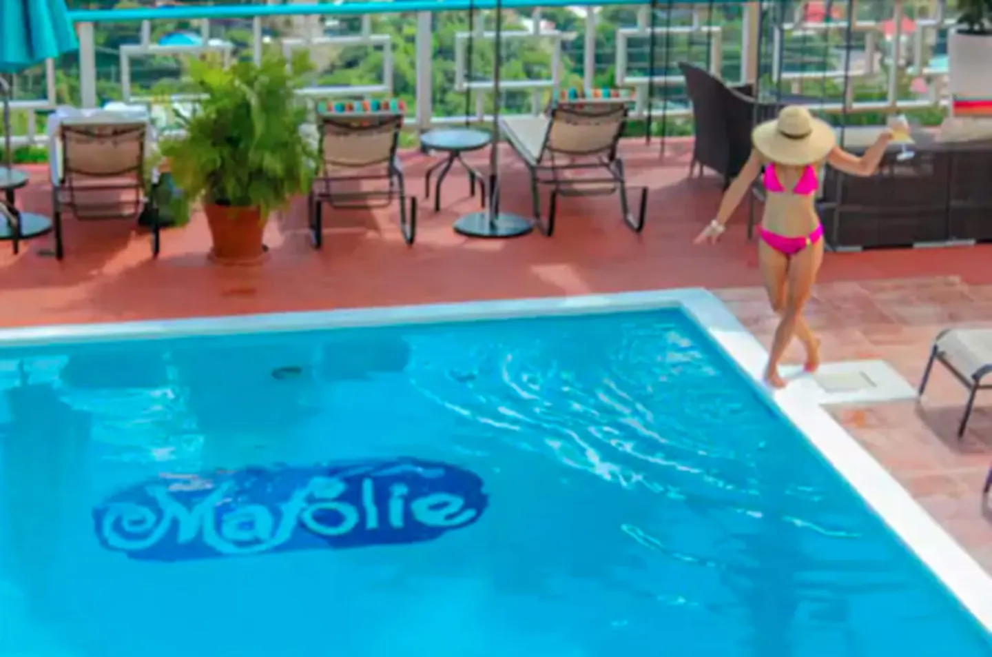Guest walking beside the Mafolie Hotel pool with logo visible underwater.