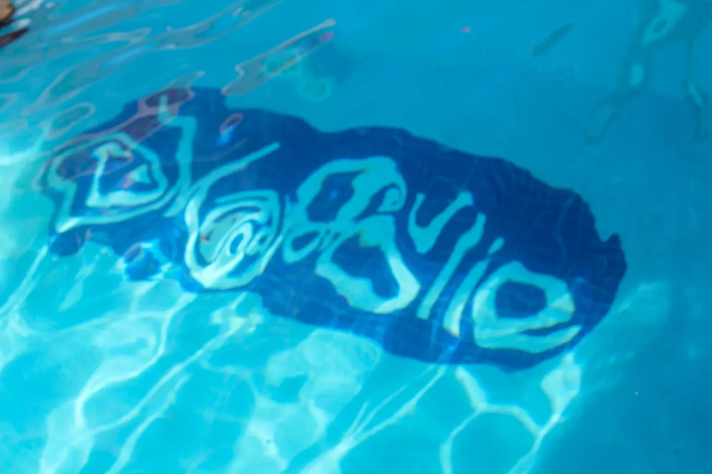 Underwater Mafolie tile logo in the swimming pool at Mafolie Hotel with rippling blue water.