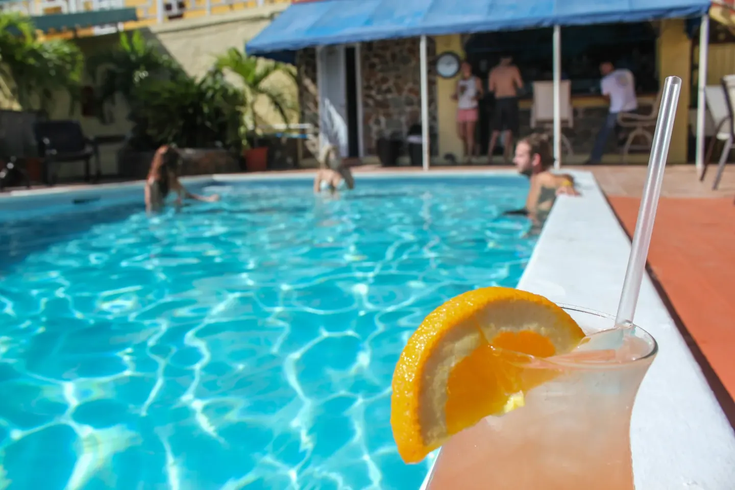 A poolside cocktail with swimmers in the background at Mafolie Hotel.