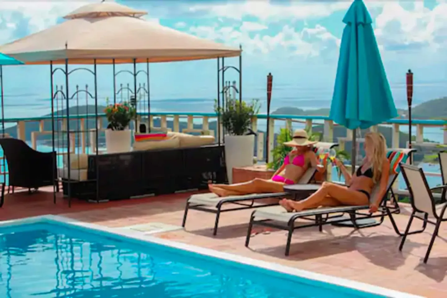 Guests relaxing on lounge chairs beside the pool at Mafolie Hotel with umbrellas and sea views.