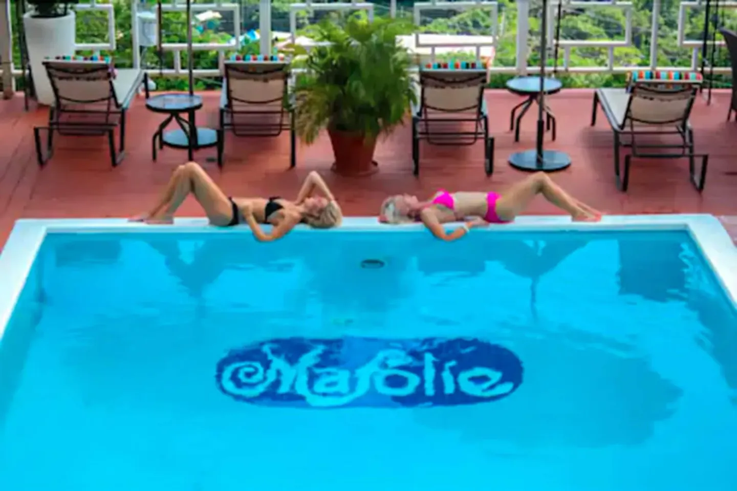 Guests relax beside the Mafolie Hotel pool with lounge chairs and a potted fern on the deck.