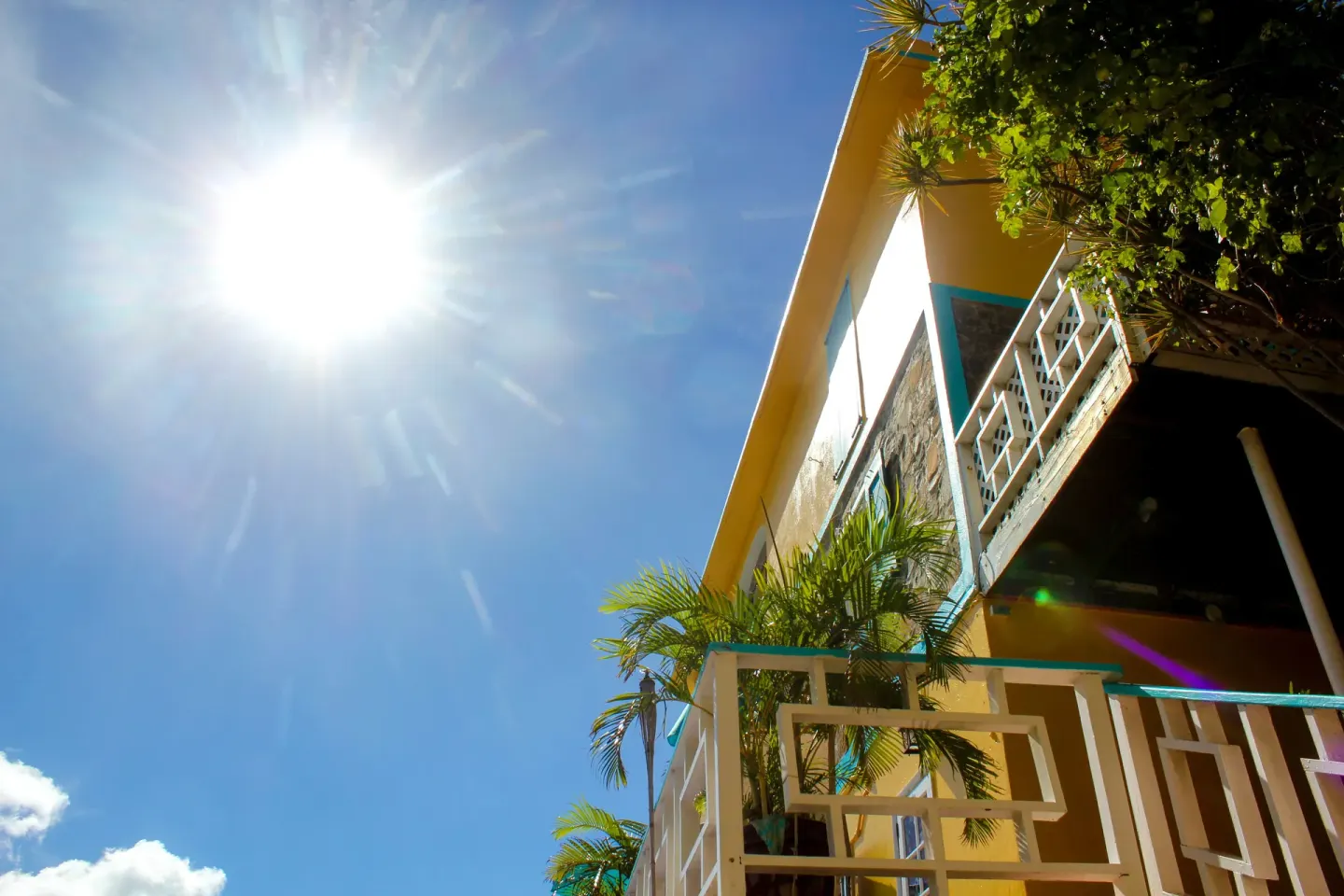 Sunlit yellow exterior with balconies and palm fronds at Mafolie Hotel.