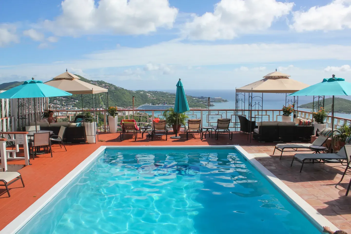 Swimming pool at Mafolie Hotel with umbrellas, lounge seating, and a wide Caribbean harbor view.