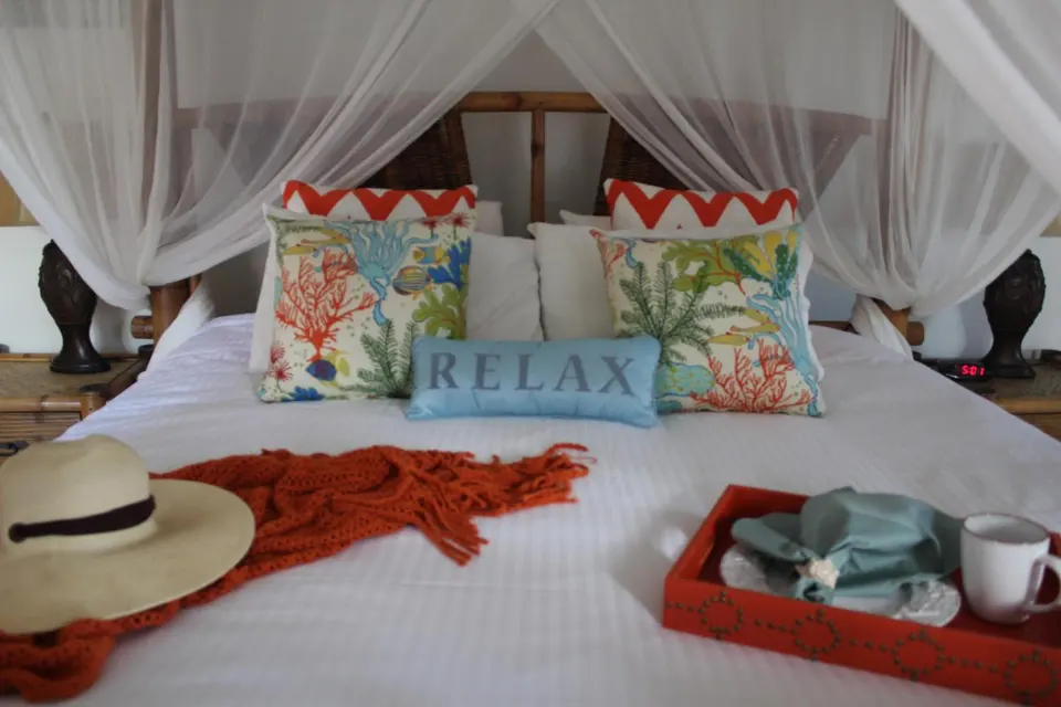 Deluxe Room canopy bed with colorful pillows and breakfast tray at Mafolie Hotel.