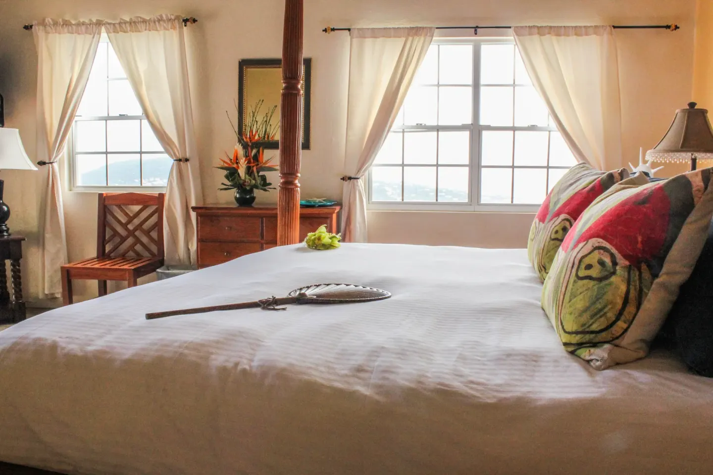 Deluxe Room bed with windows, dresser, and island light at Mafolie Hotel.