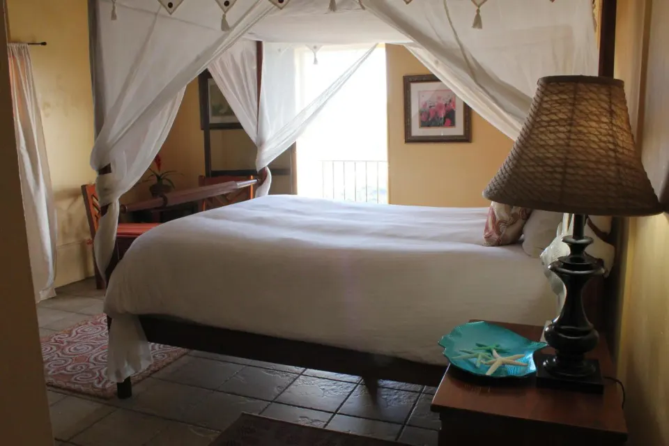 Deluxe Room four-poster bed with sheer drapes and bedside lamp at Mafolie Hotel.