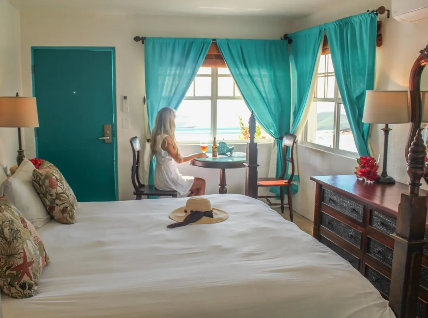 Deluxe Room bed with turquoise curtains and sitting area at Mafolie Hotel.