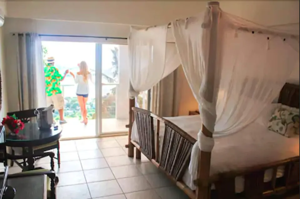 Junior Suite Harbor View with canopy bed beside balcony doors at Mafolie Hotel.