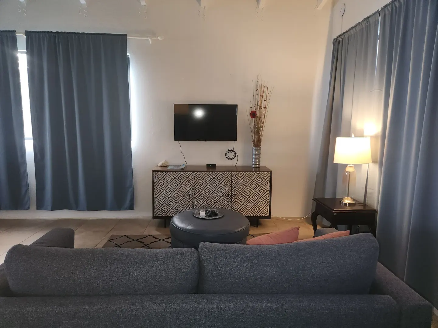 Panoramic Villa living room with sofa, TV, curtains, and lamp at Mafolie Hotel.