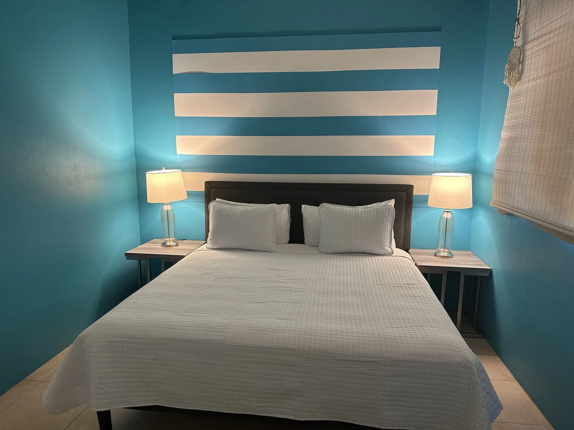 Panoramic Villa at Mafolie Hotel with white bed, turquoise accent wall, and sweeping Charlotte Amalie harbor views in St. Thomas, U.S. Virgin Islands.