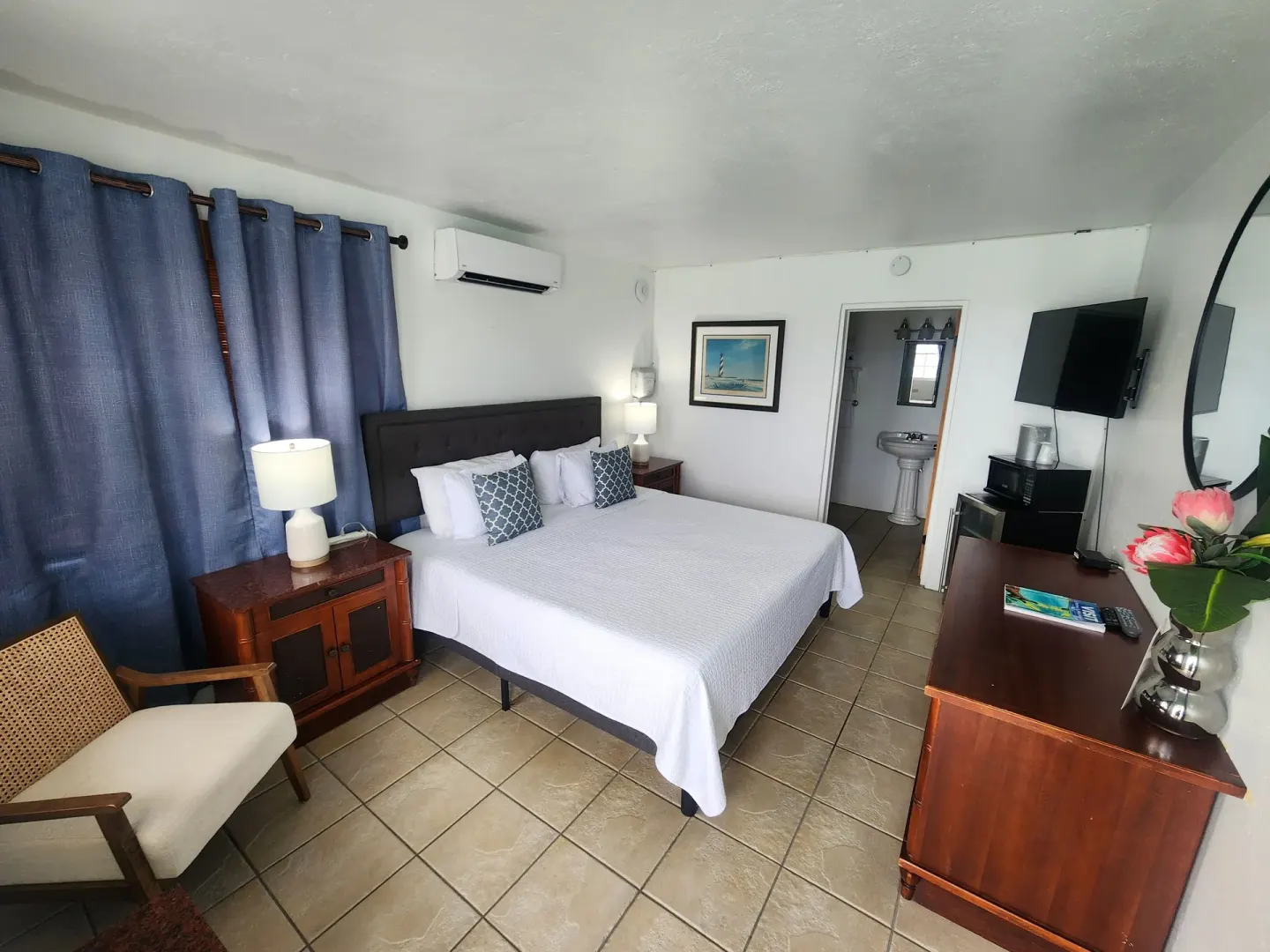 Standard Room with bed, blue curtains, wall TV, dresser, and bathroom doorway at Mafolie Hotel.