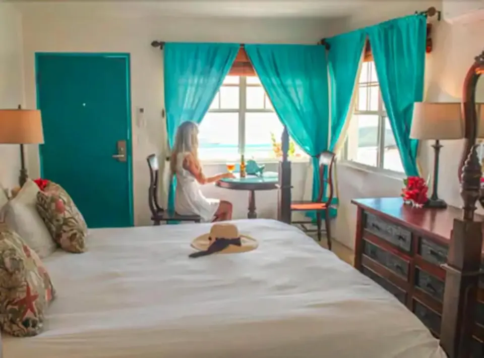 Standard Room with bed, turquoise curtains, dresser, and window seating at Mafolie Hotel.