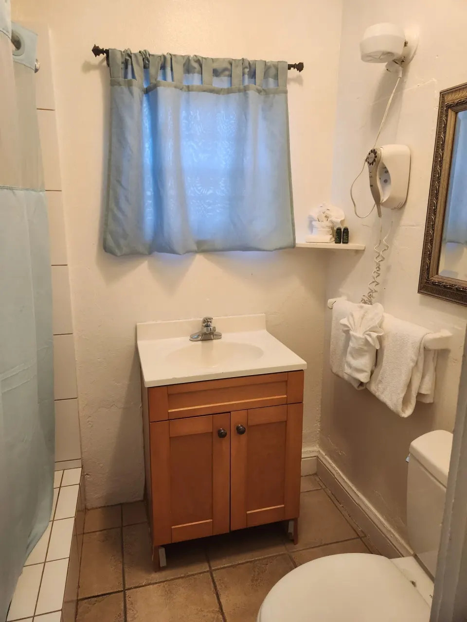 Bathroom for the Tiny Room with vanity, shower curtain, towels, and wall mirror at Mafolie Hotel.