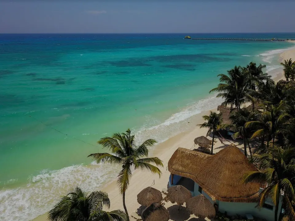 Aerial view of turquoise Caribbean beach and thatched beach structures at Mahekal Beach Front Resort & Spa