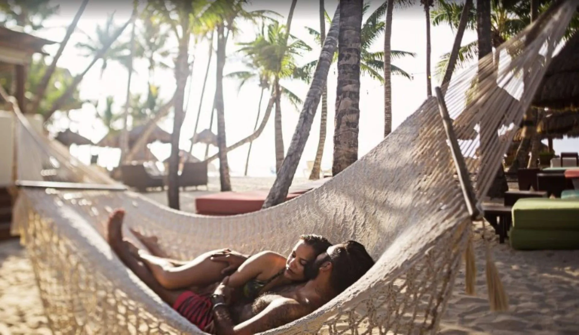 Couple rests in a beach hammock at Mahekal Beach Front Resort & Spa.