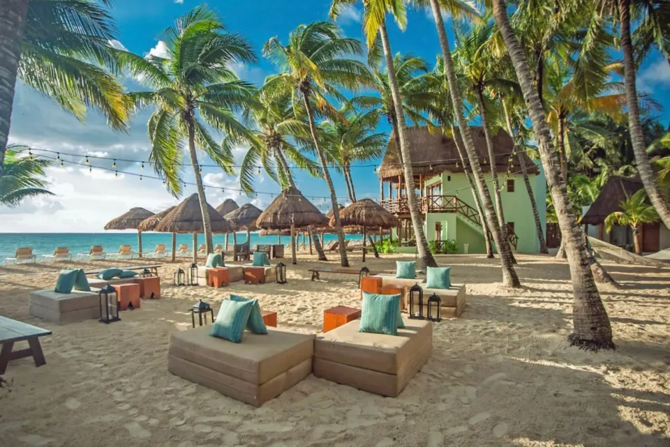 Sandy beachfront lounge seating and palapas at Mahekal Beach Front Resort & Spa