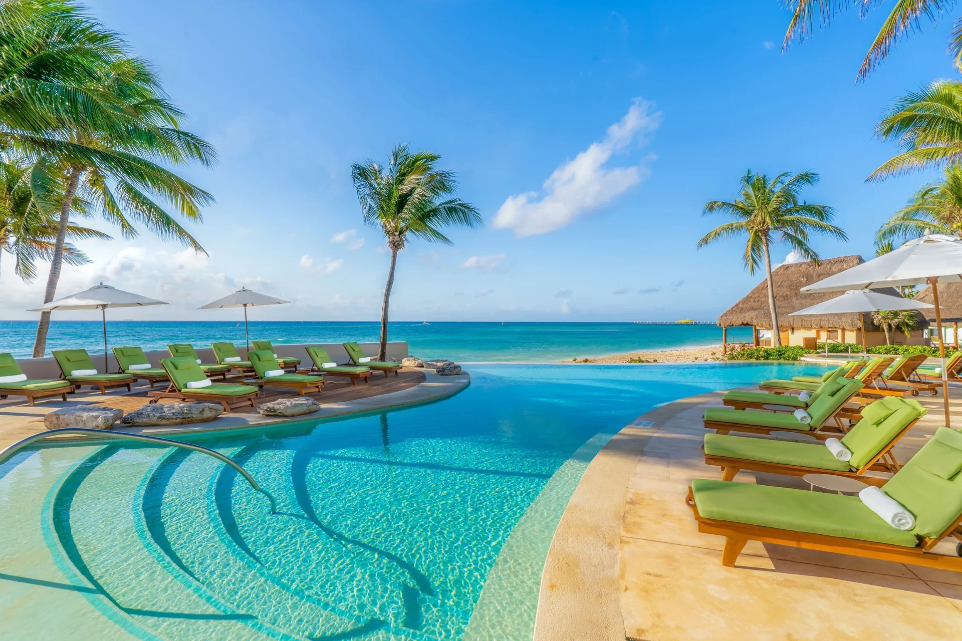 Beachfront pool with green loungers at Mahekal Beach Front Resort & Spa.