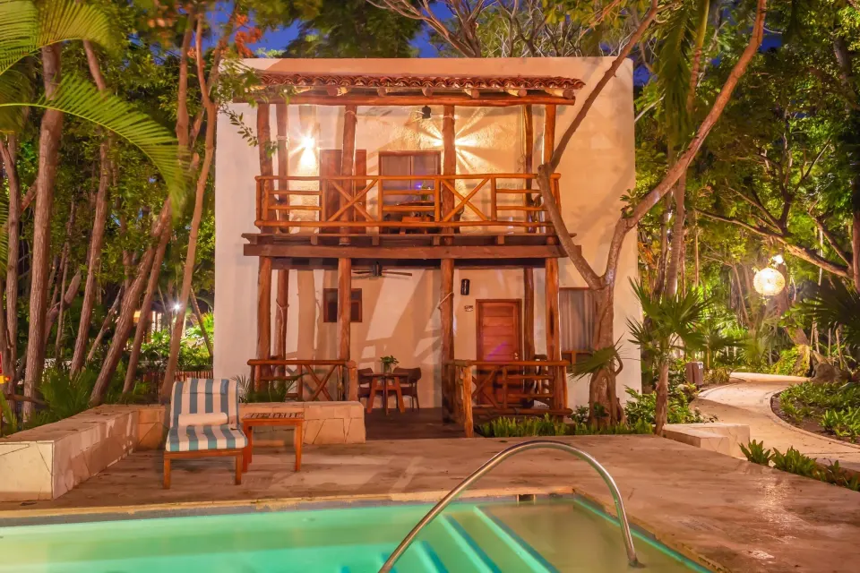 Two-story bungalow with private terrace beside a lit pool at Mahekal Beach Front Resort & Spa