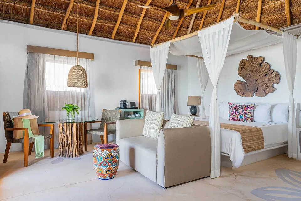 Canopy bed suite with seating and table at Mahekal Beach Front Resort & Spa