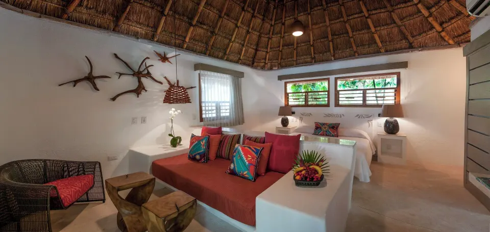 Cozy palapa suite with built-in sofa and bed at Mahekal Beach Front Resort & Spa