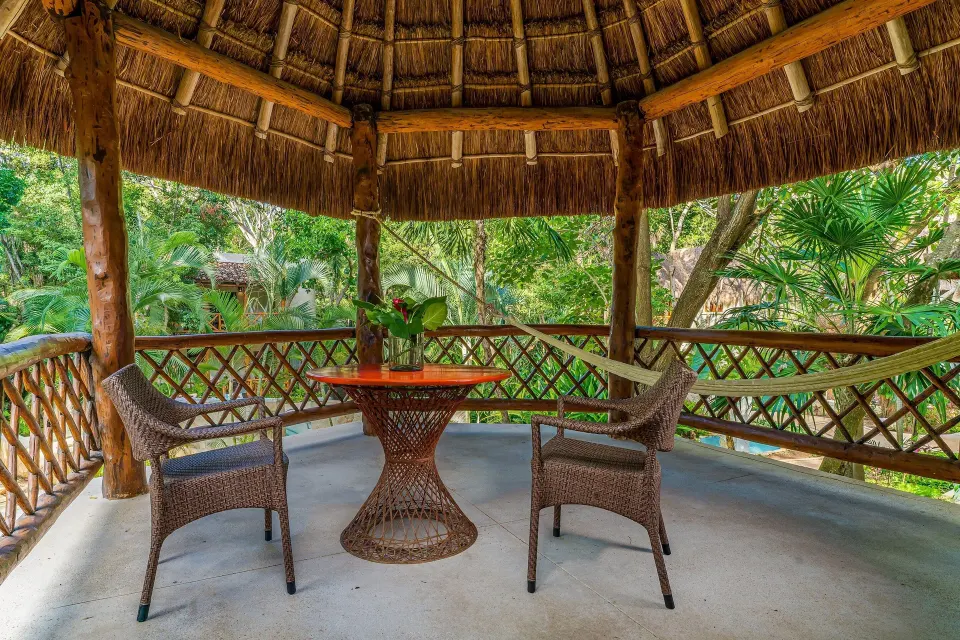 Shaded palapa gazebo with table and chairs overlooking lush gardens at Mahekal Beach Front Resort & Spa