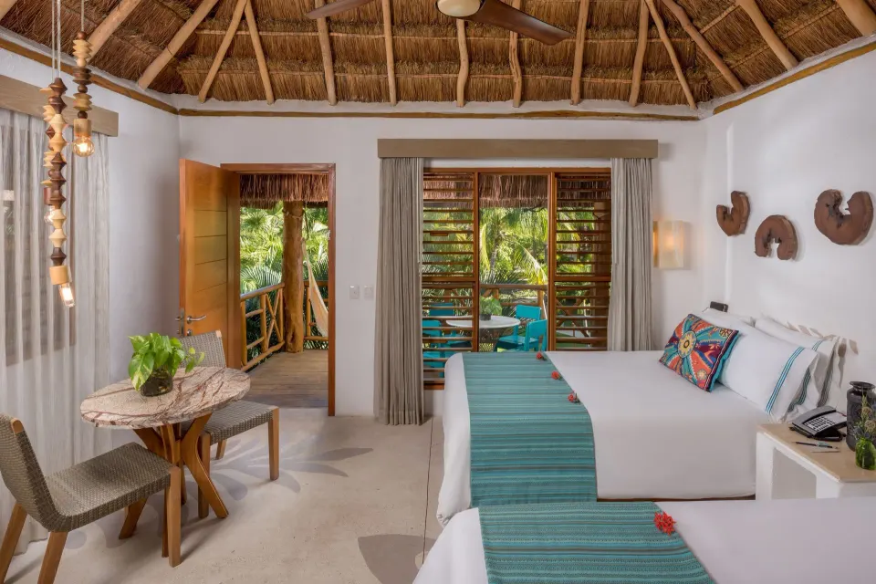 Twin-bed room opening to a leafy balcony at Mahekal Beach Front Resort & Spa