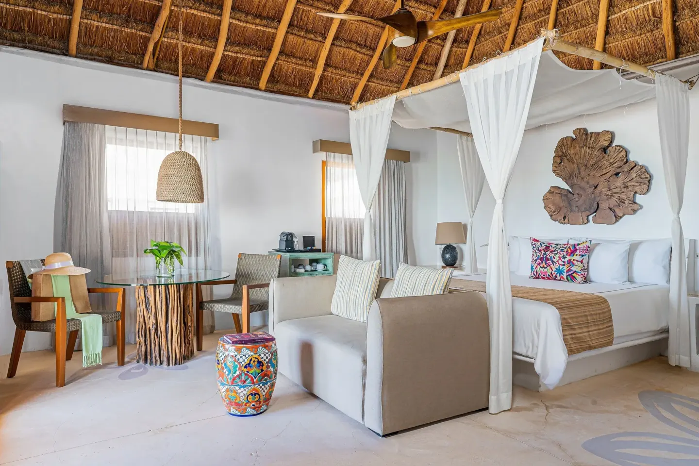 Thatched-roof guest room with canopy king bed at Mahekal Beach Front Resort & Spa.
